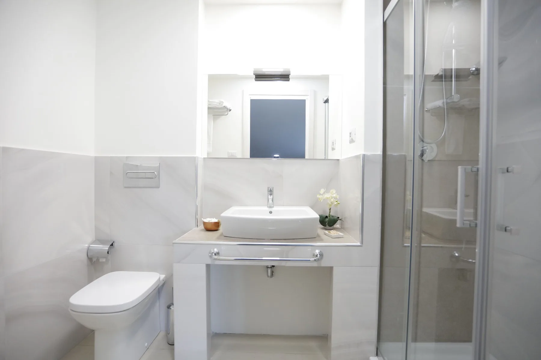 A bright bathroom with a sink, toilet, and glass shower.
