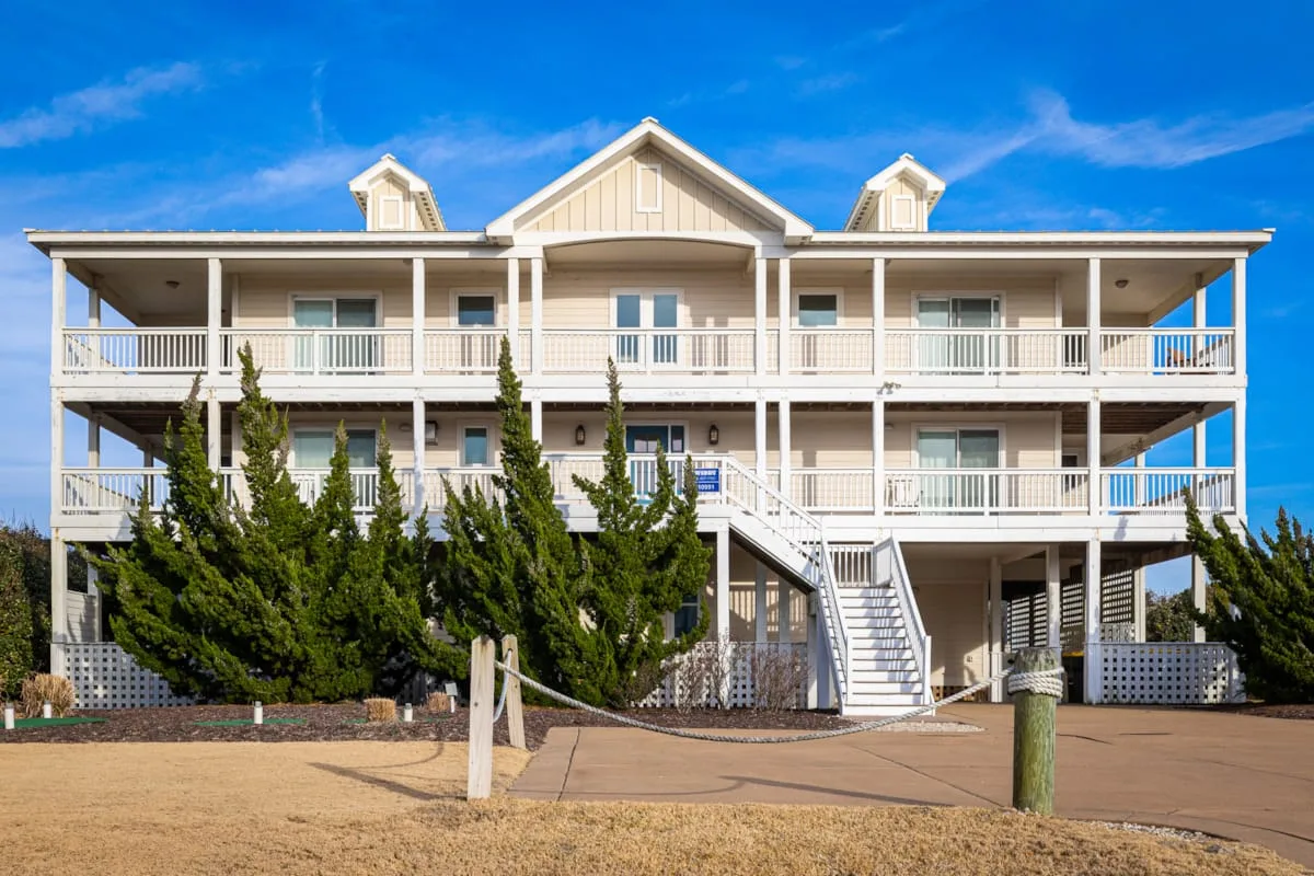 Una casa elevada de estilo costero con balcones blancos y escaleras exteriores.