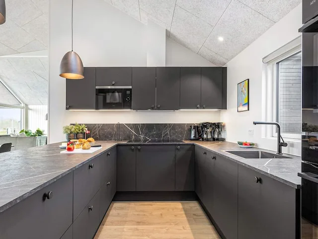 A modern kitchen with dark cabinets, gray countertops, and a central work area.