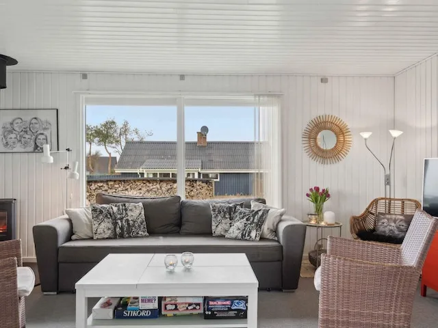 Una sala luminosa con un sofá gris y una mesa de centro blanca.