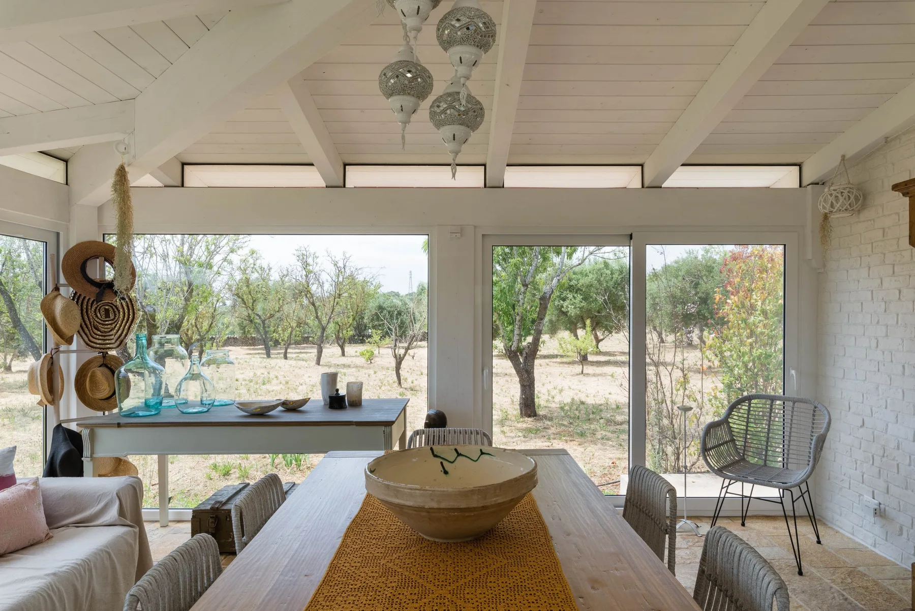 A bright dining area opens onto a tree-filled outdoor view.