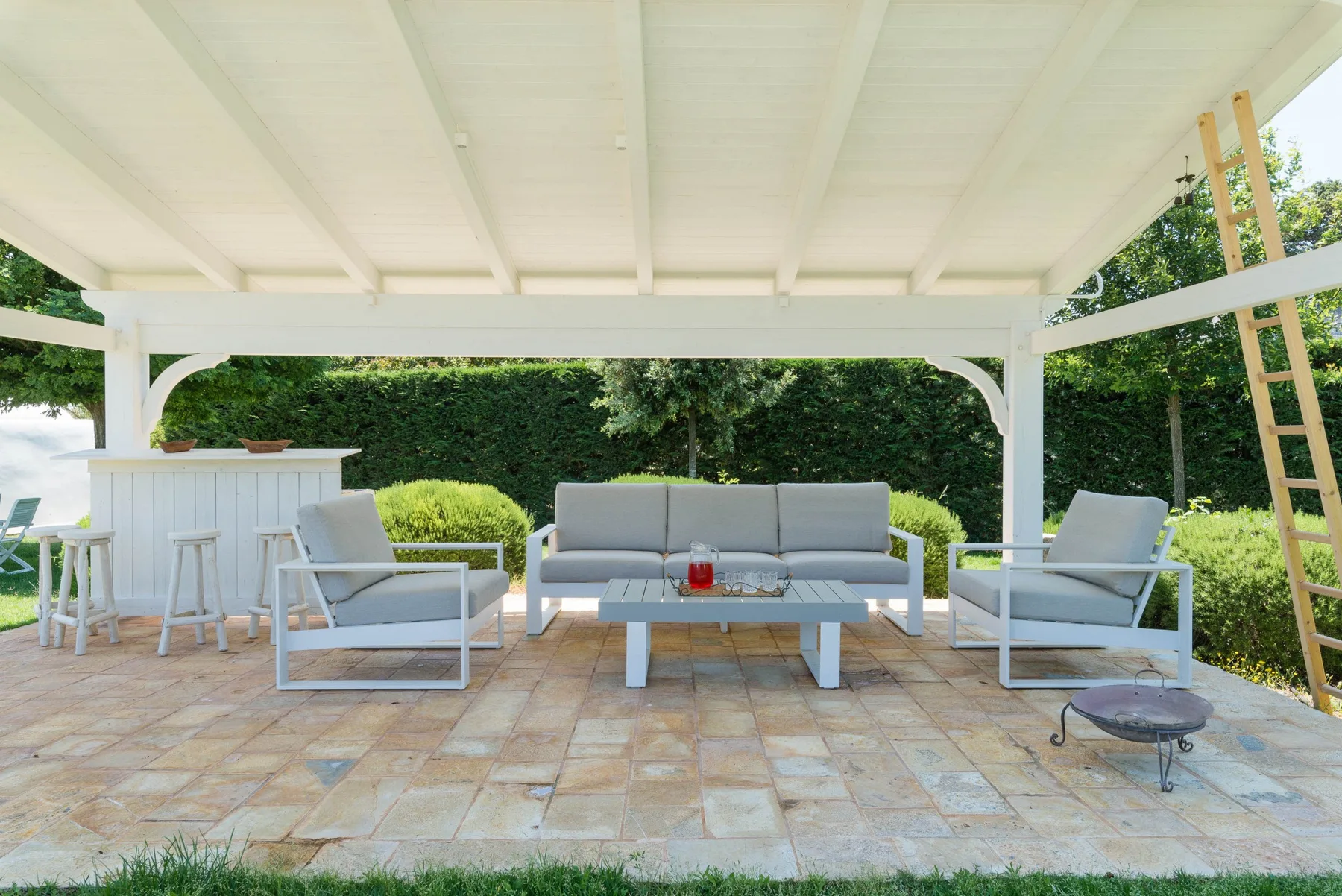A covered outdoor seating area with a sofa, chairs, and a tiled patio.