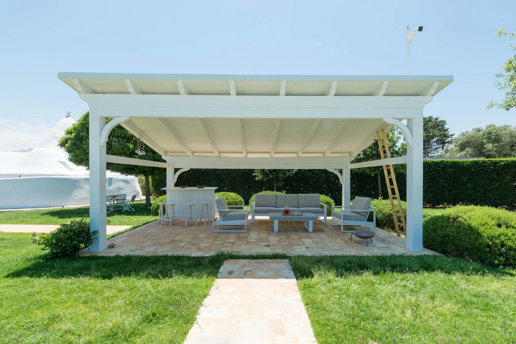 A covered outdoor seating area with a table and chairs overlooks the water.
