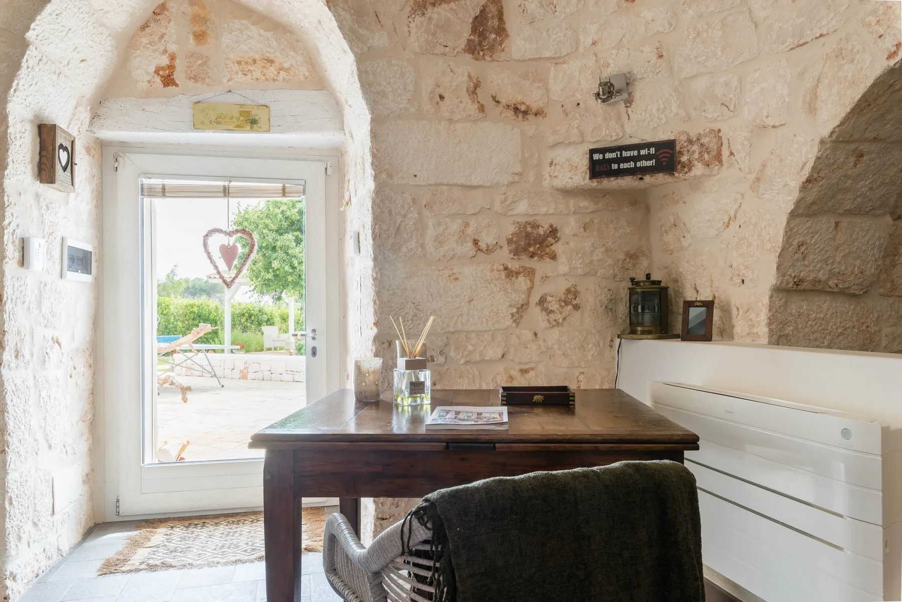 A stone-walled room with a wooden desk beside a large window.