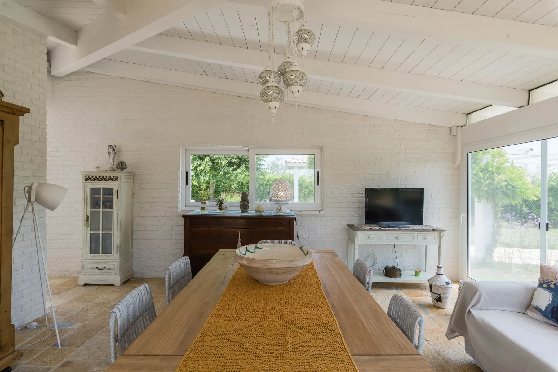 A bright dining room with a long wooden table and large windows.