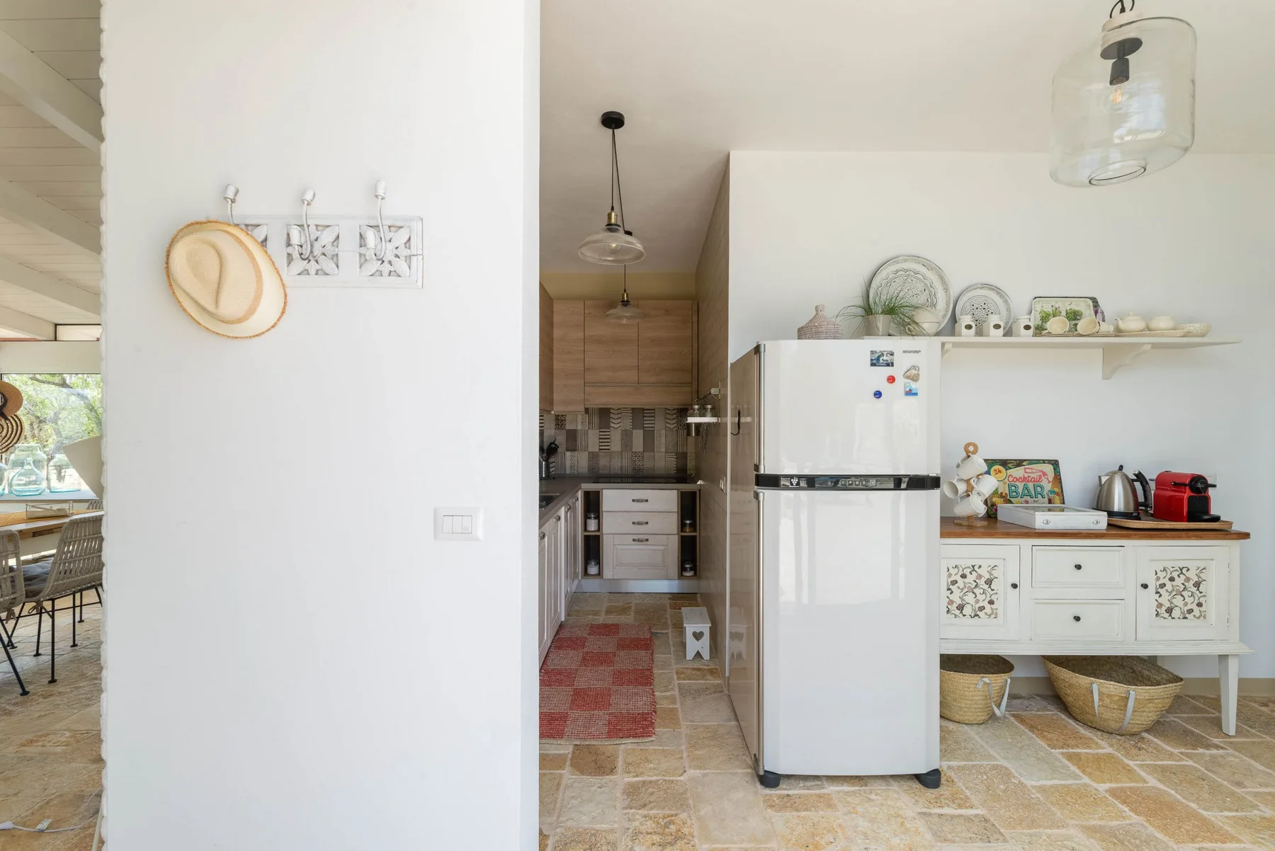 A bright kitchen with a refrigerator, wooden cabinets, and a white dining hutch.