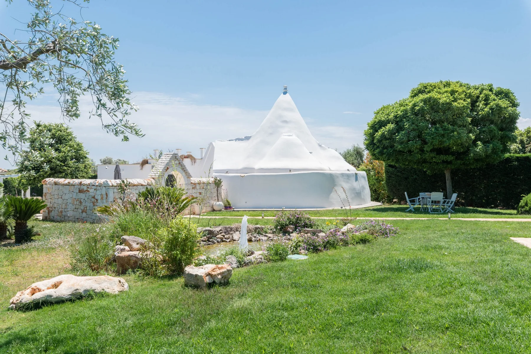 A landscaped garden with a distinctive white building and outdoor seating.