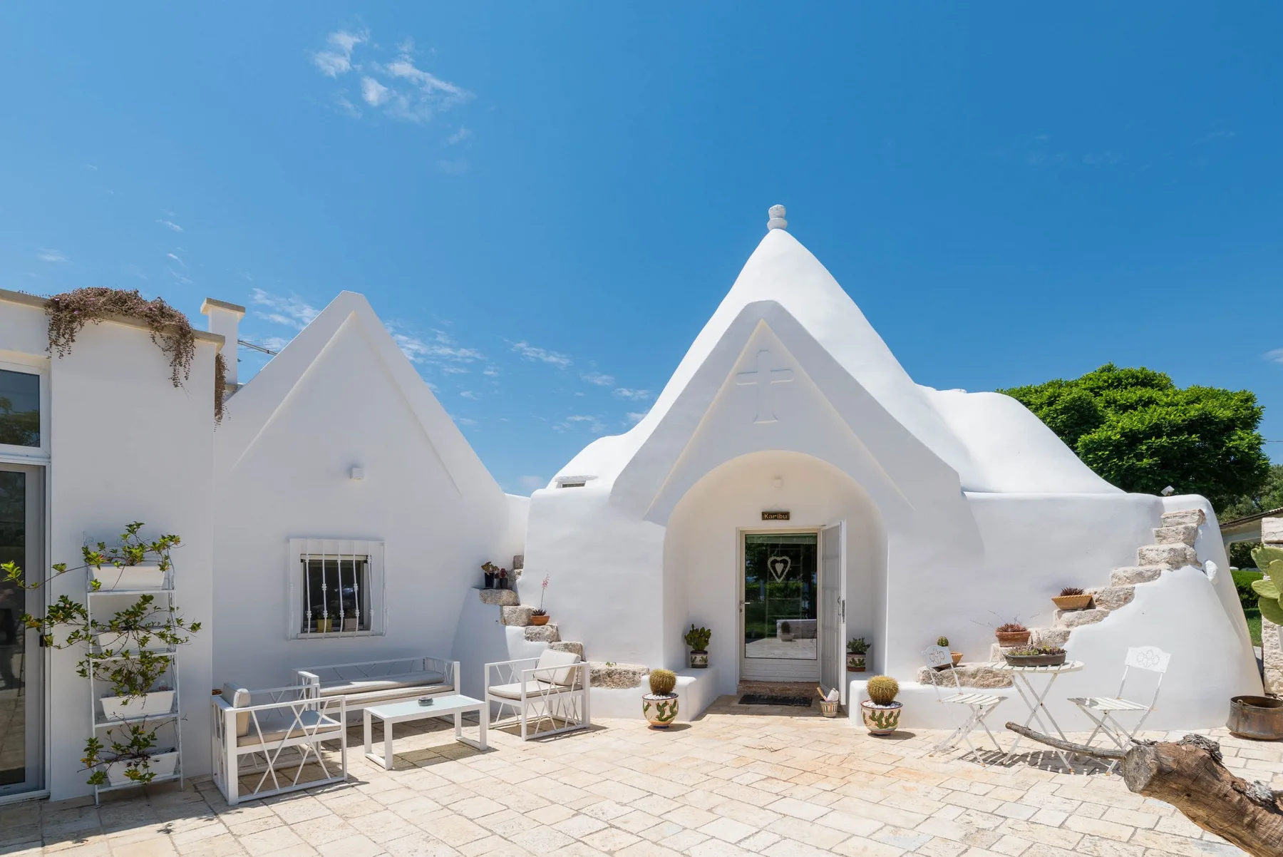 A white stucco building with pointed rooflines and an outdoor paved seating area.