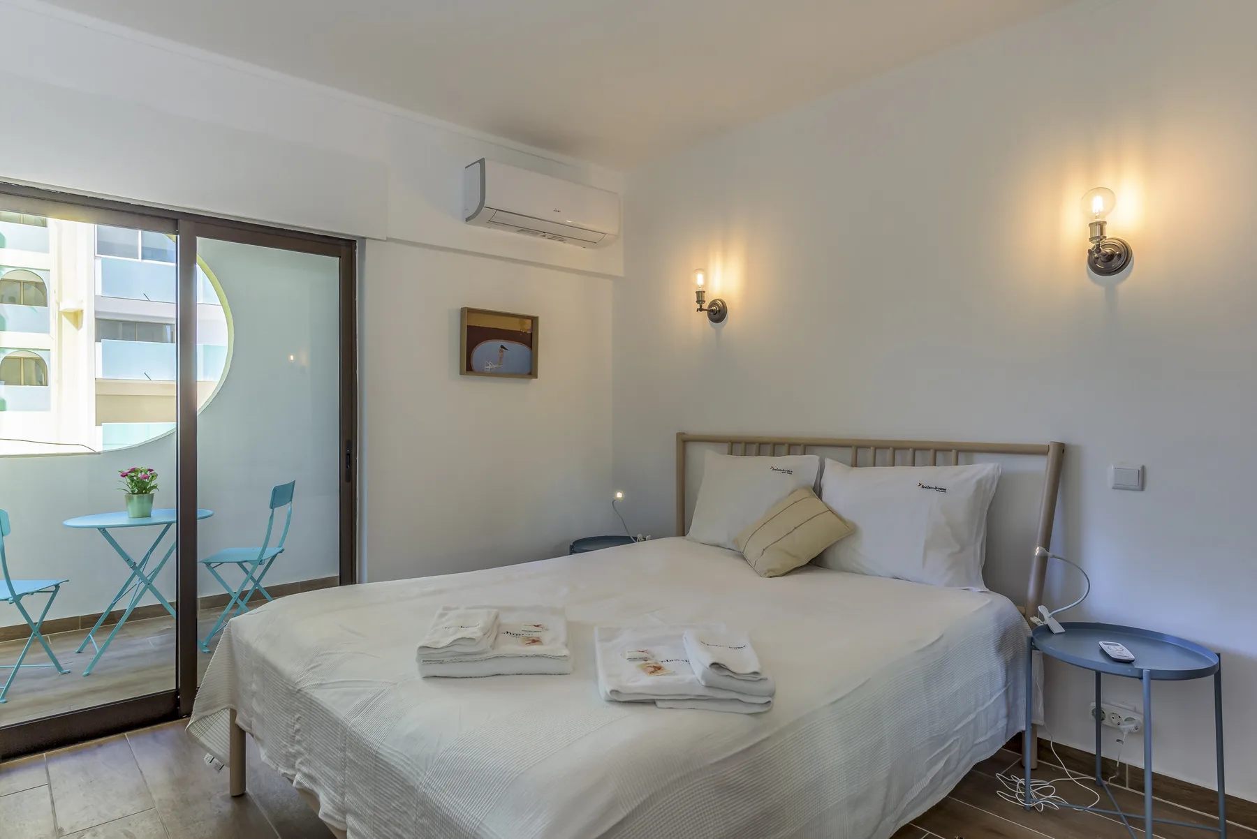 A bedroom with a large bed, bedside tables, and a sliding glass door to a balcony.