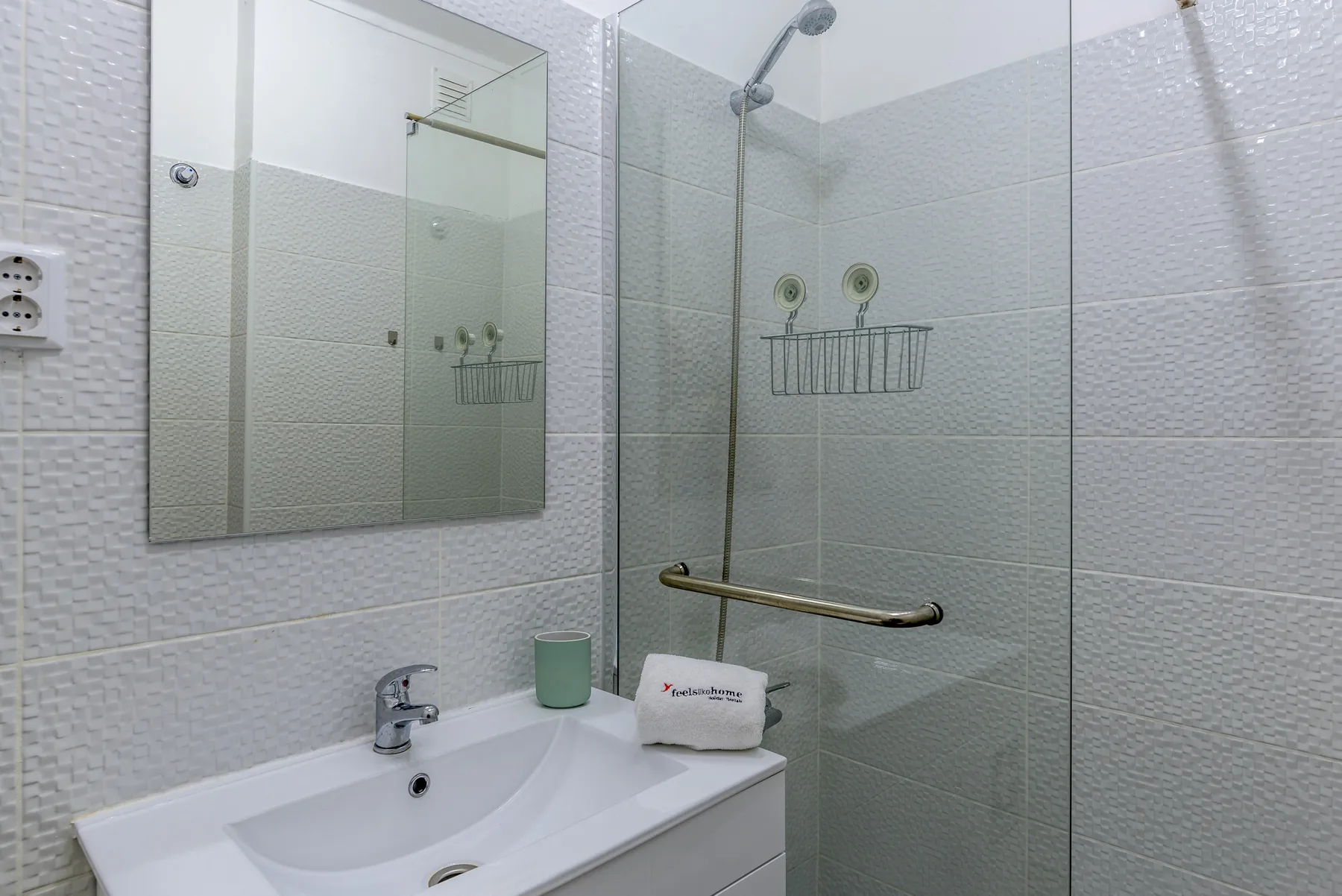A bright bathroom with a sink, mirror, and glass shower.