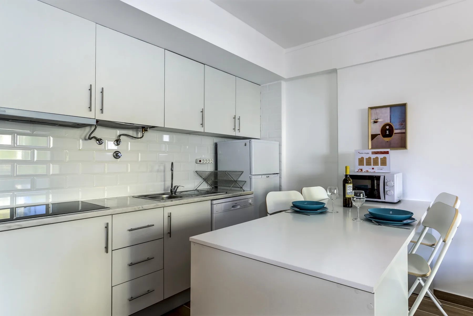 A bright kitchen with white cabinets, a countertop, and a dining island.