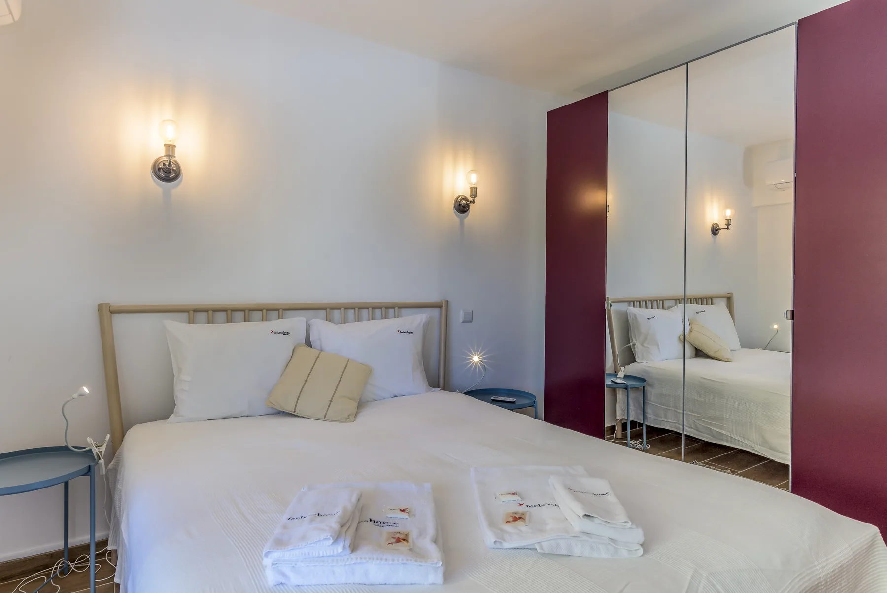 A bedroom with a neatly made bed and mirrored wardrobe.