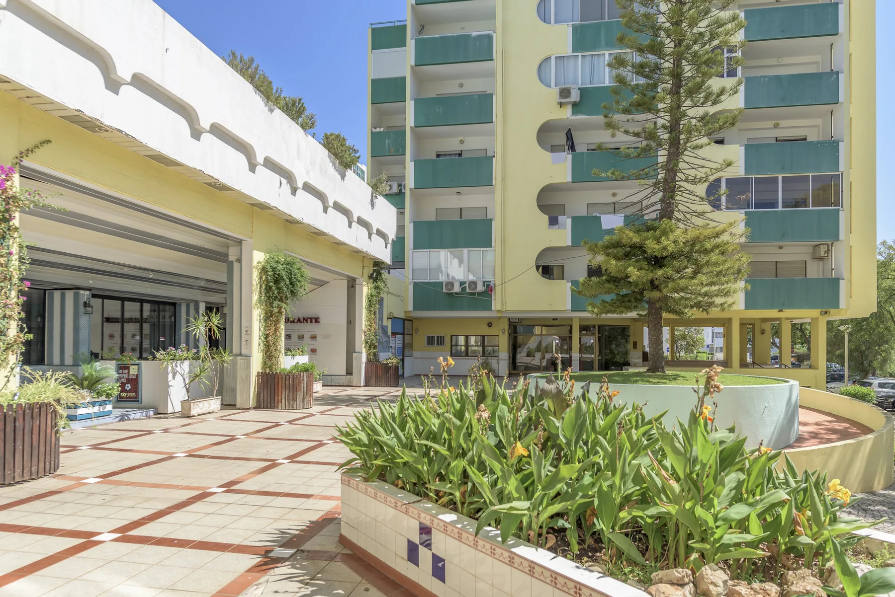 Apartment courtyard with planted garden beds and a multi-story building.