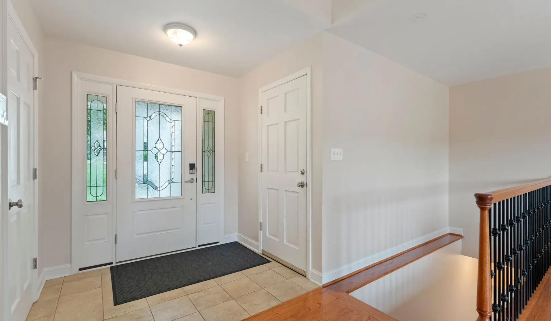 Una entrada con una puerta principal que tiene paneles de vidrio decorativos.