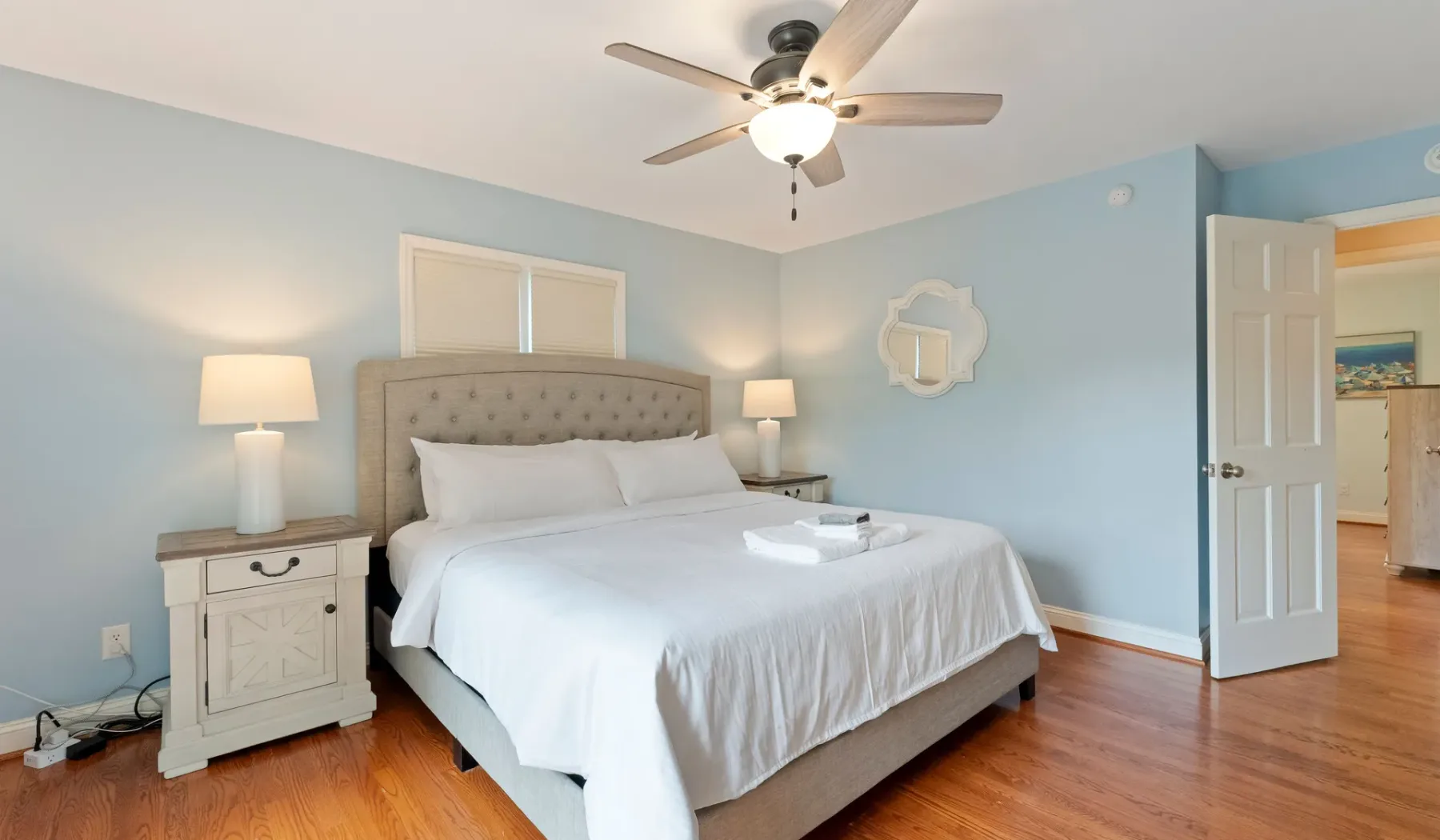Un dormitorio con una cama bien tendida, mesas de noche y un ventilador de techo.