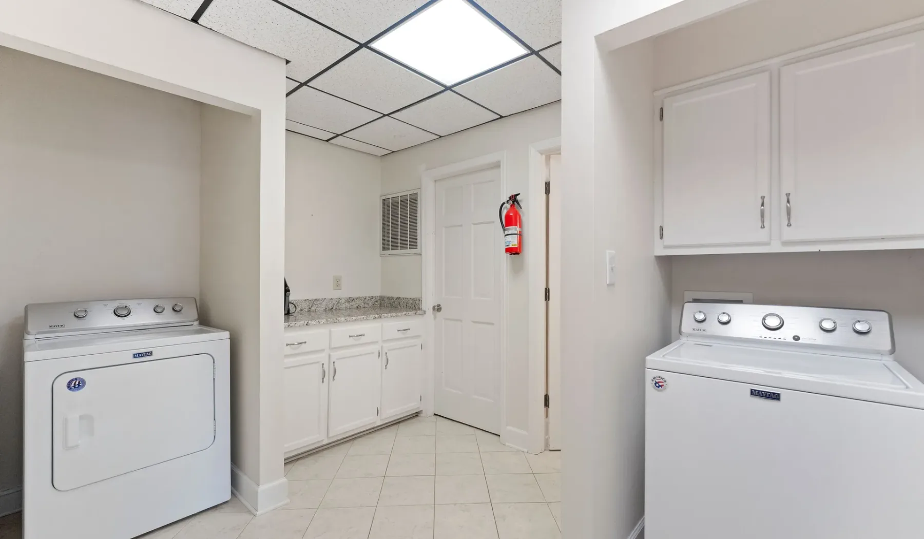 Un cuarto de lavandería con electrodomésticos blancos y armarios empotrados.
