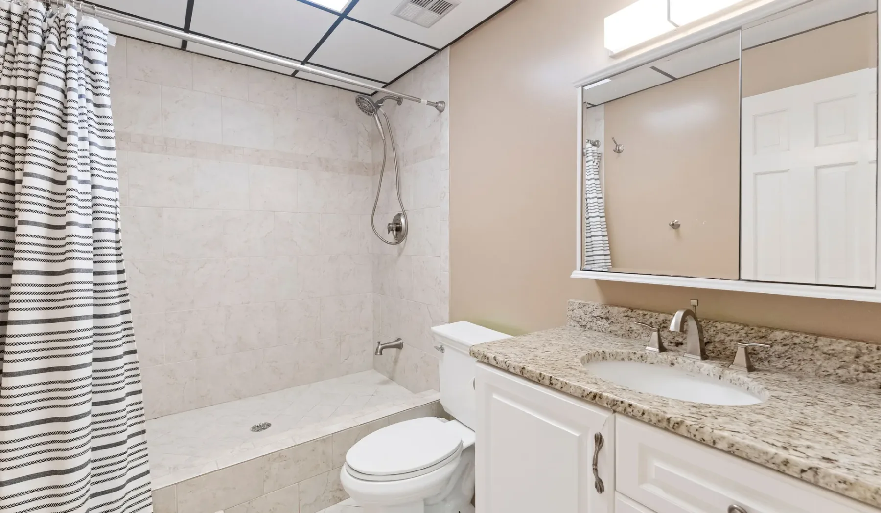 Un baño con ducha, inodoro y mueble con lavabo.