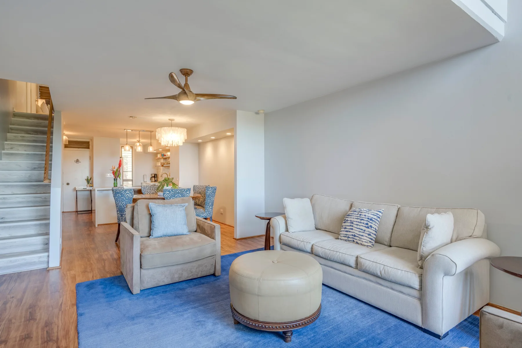 A living room with seating arranged around a blue area rug.
