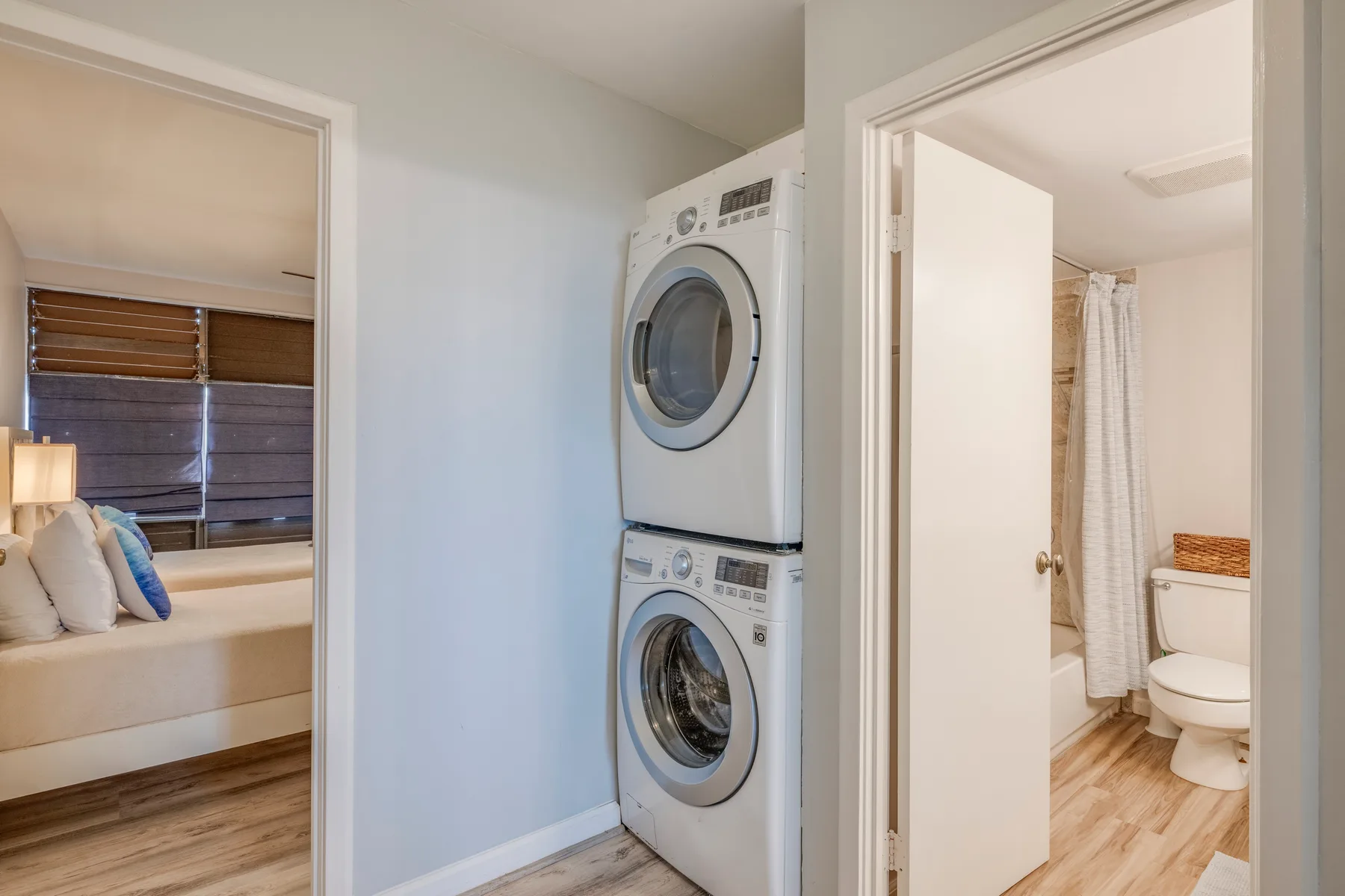 A laundry area with a stacked washer and dryer between adjoining rooms.
