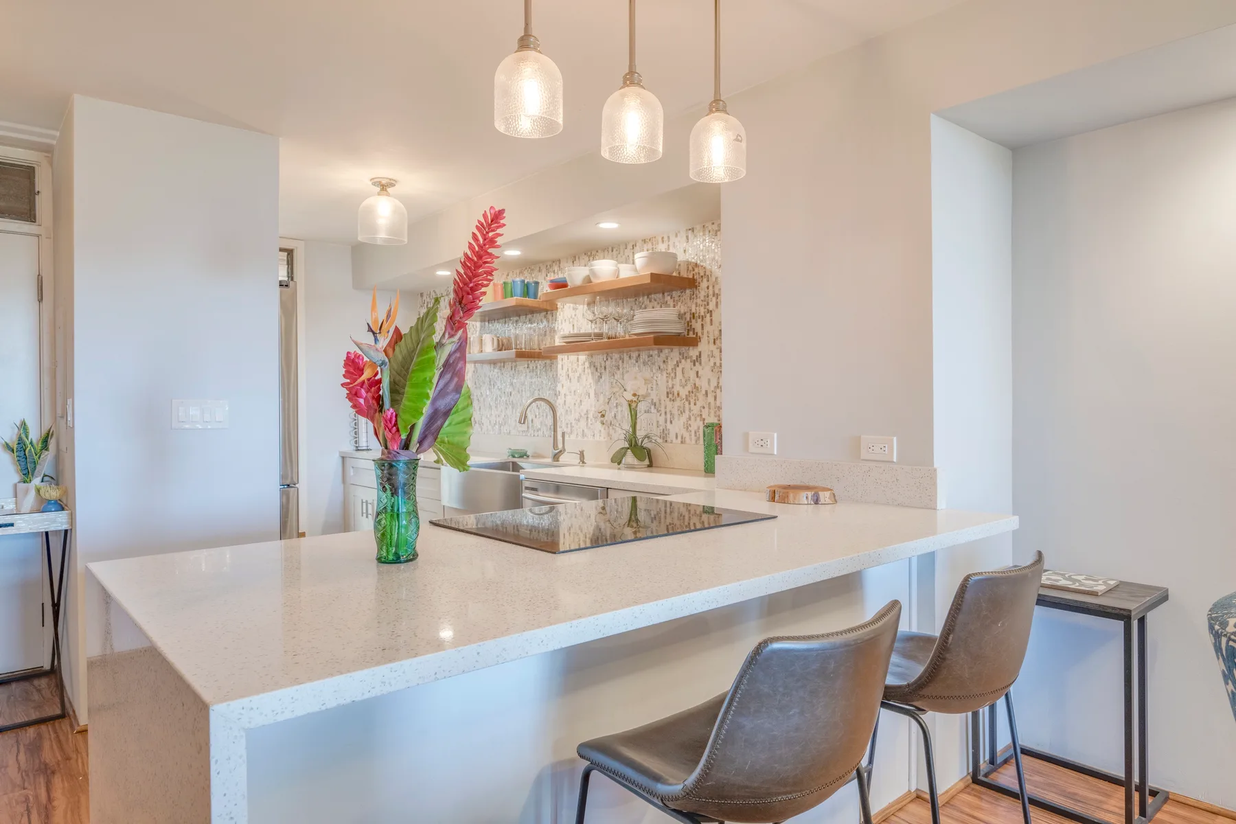 A bright kitchen with a large island and pendant lights.