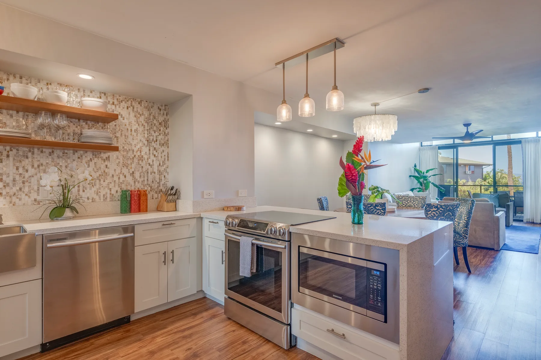 A bright kitchen with a central island, stainless steel appliances, and pendant lights.