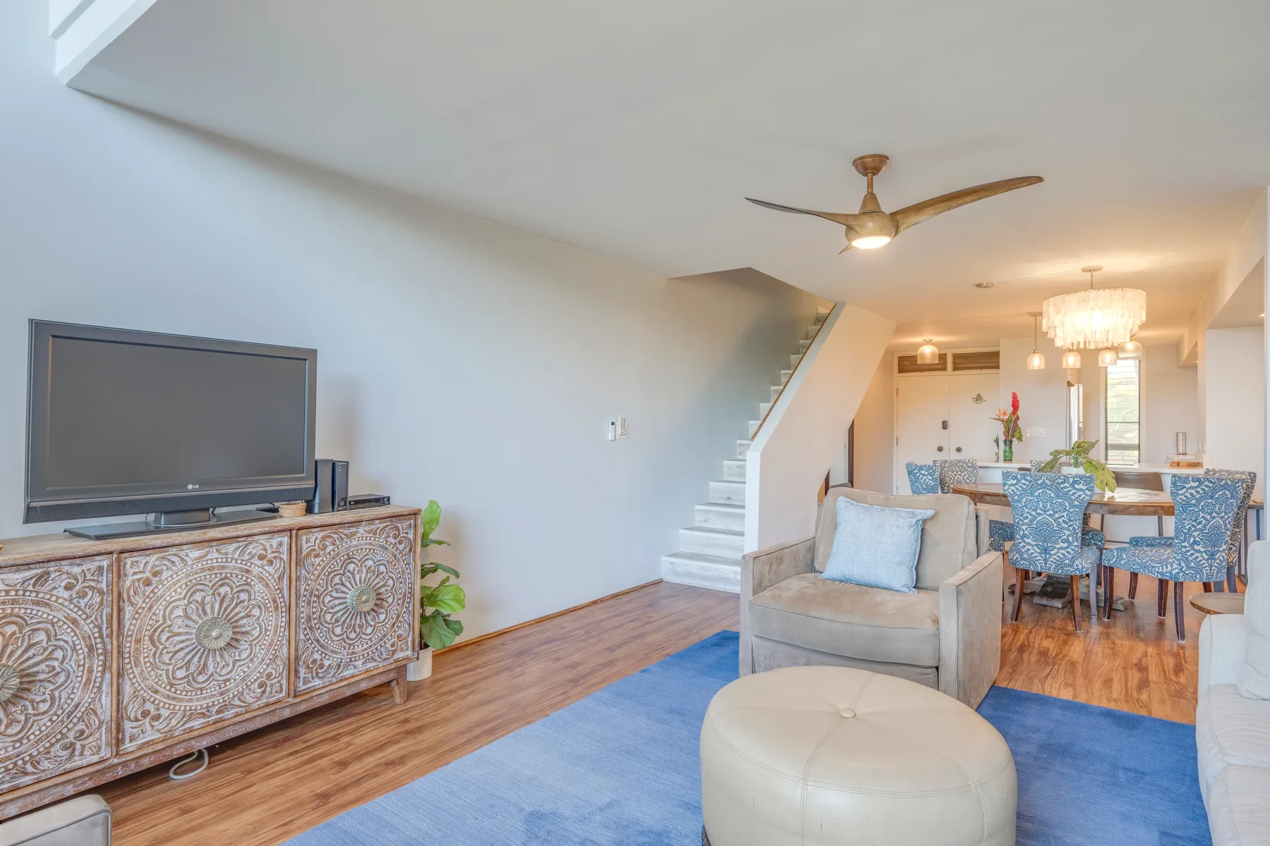 An open living and dining area with seating, a television, and a staircase.