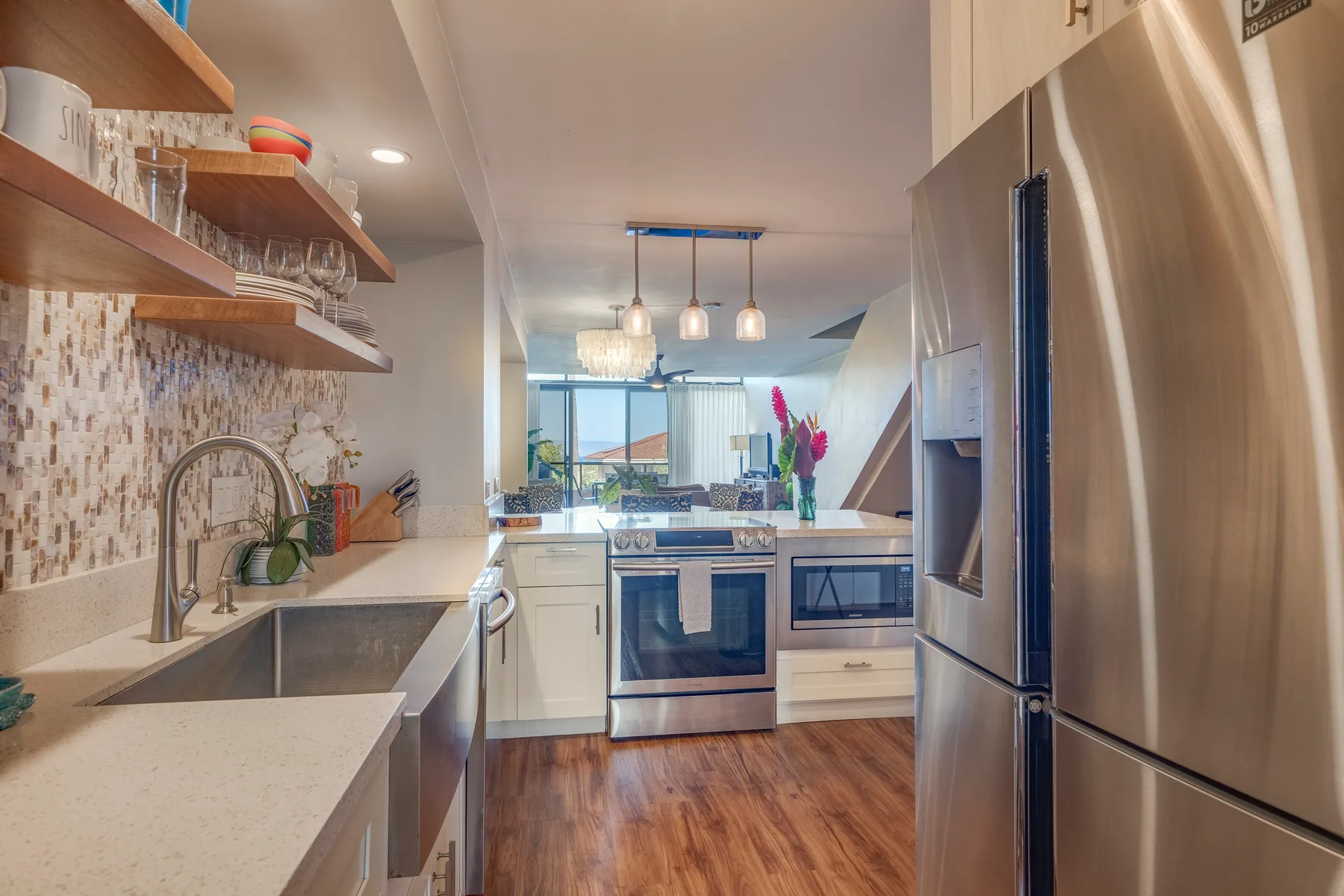 A bright kitchen with an island, stainless steel appliances, and wood flooring.