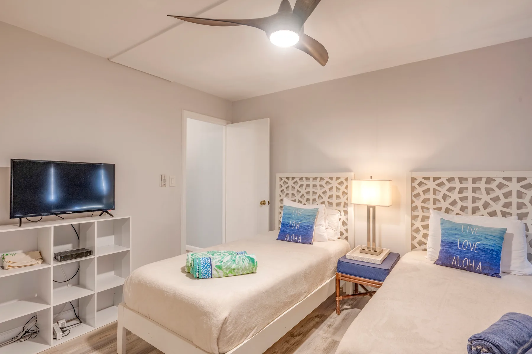 A twin bedroom with two beds, a television, and a bedside lamp.