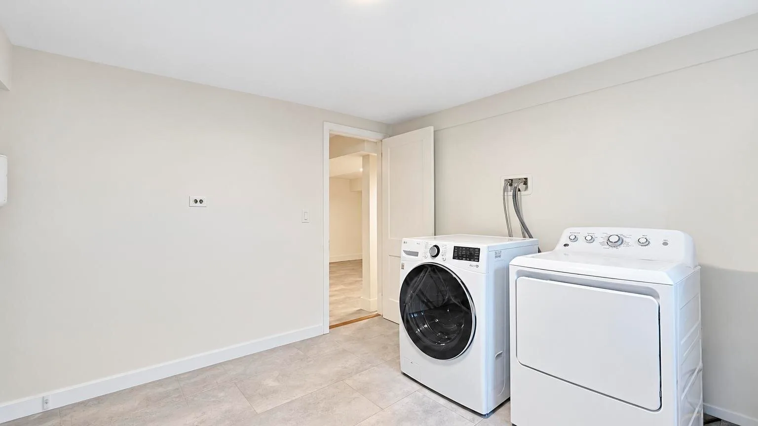 A laundry room with a front-loading washer and a dryer beside an open doorway.