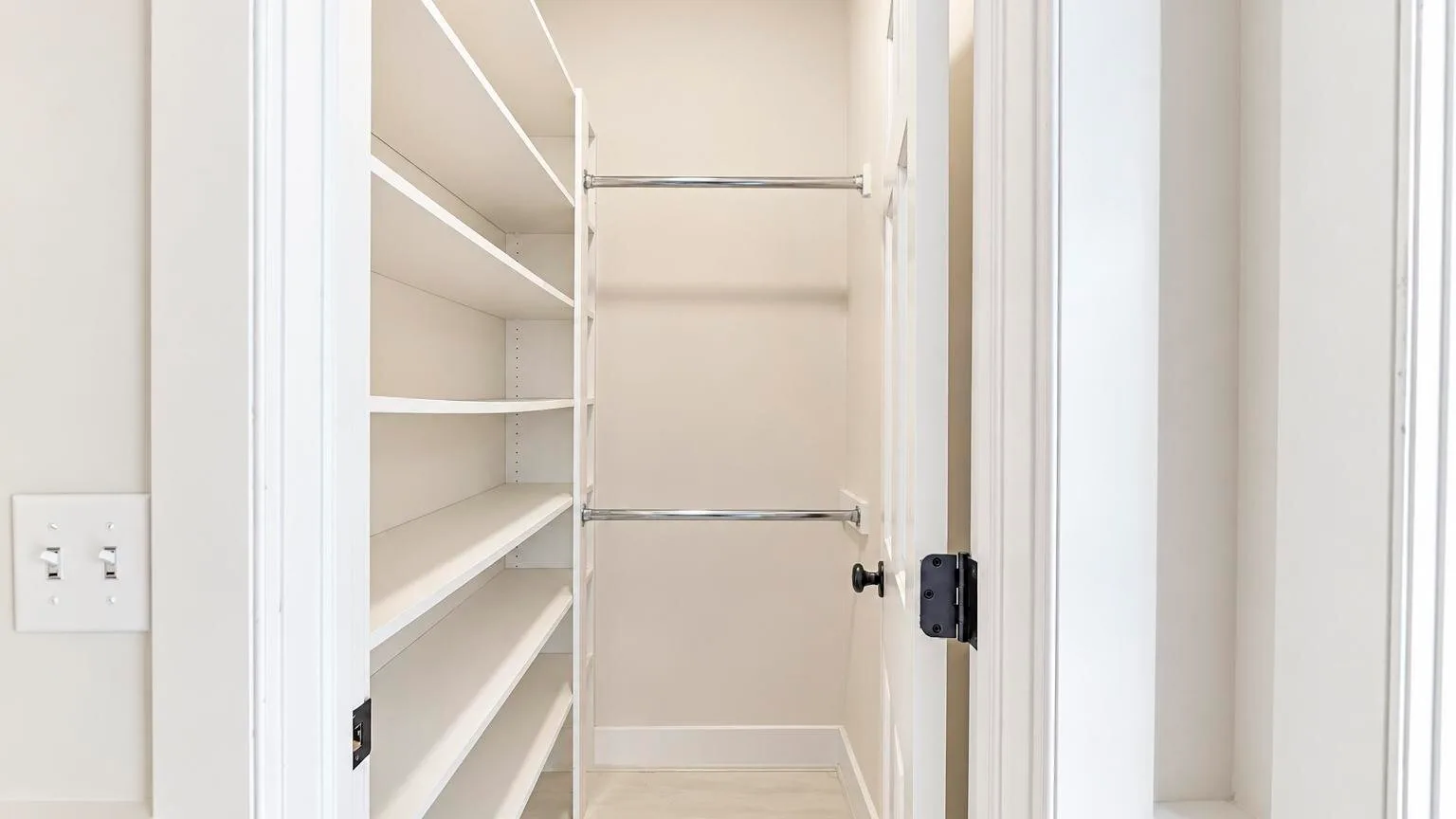 A small walk-in closet with built-in shelves and hanging rods.