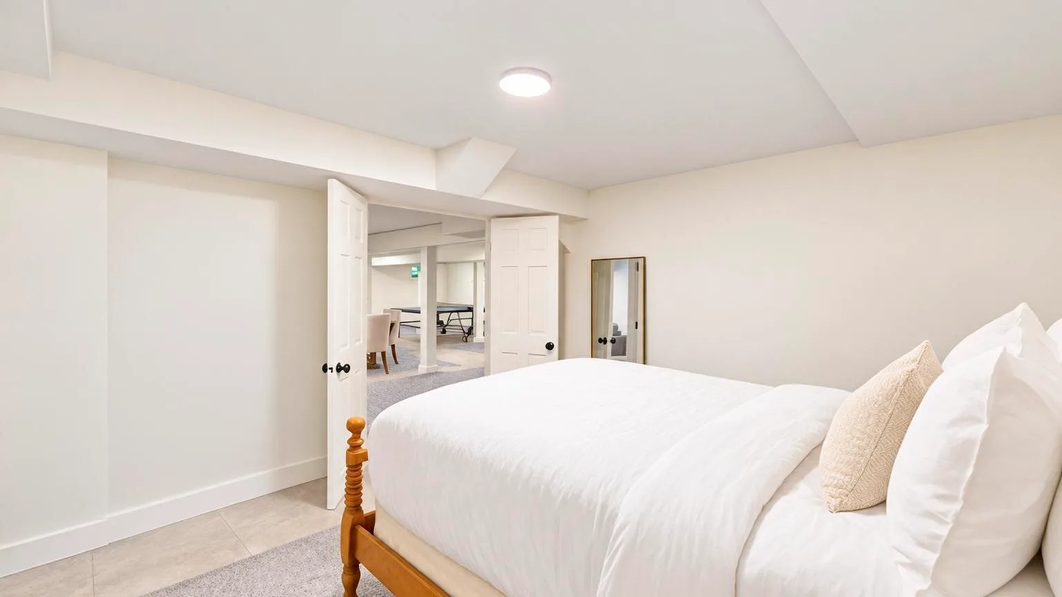 A bedroom with a bed dressed in white linens and a doorway to an adjoining room.