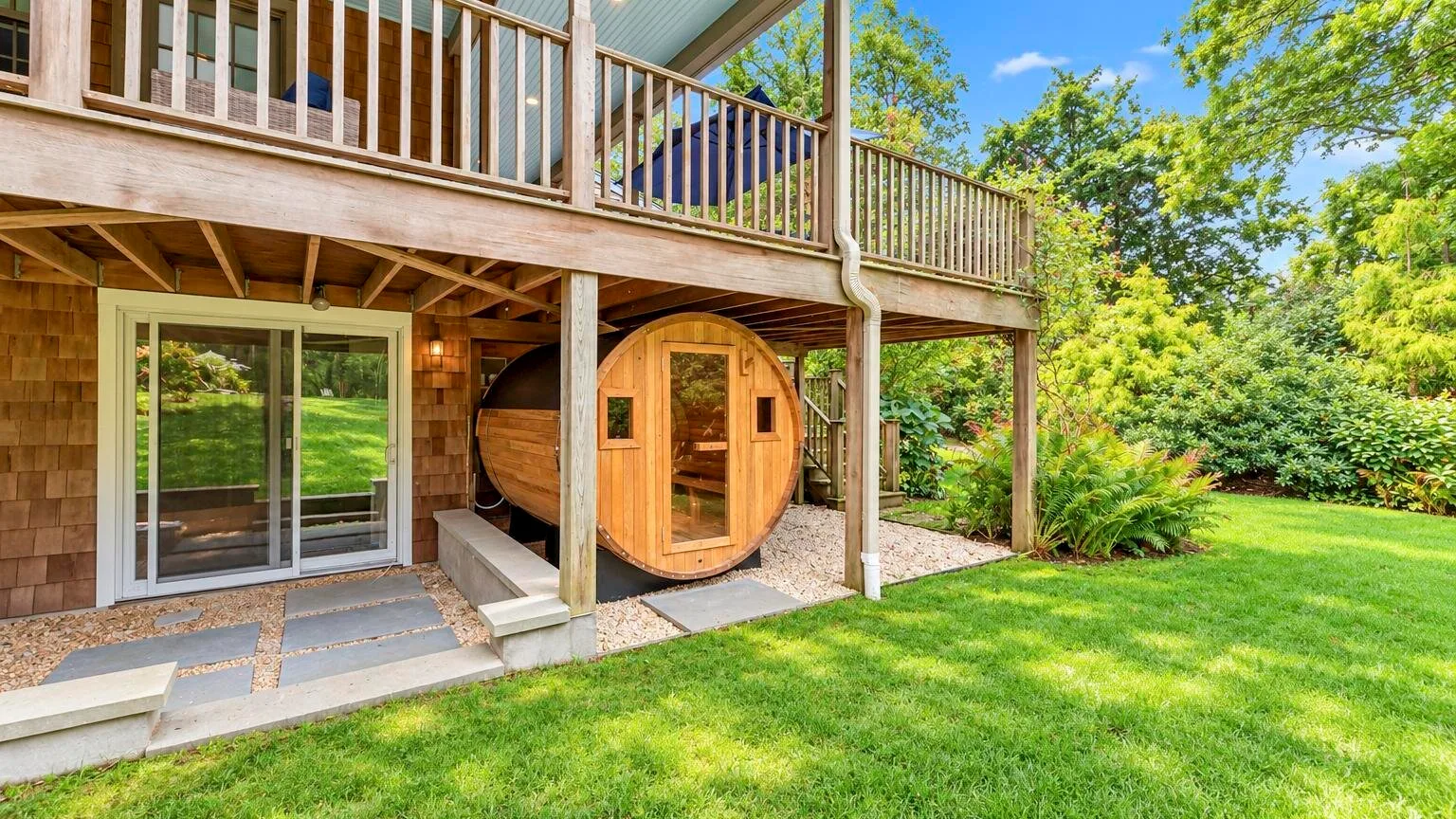 A backyard deck overlooks a grassy lawn, with a round wooden structure beneath it.