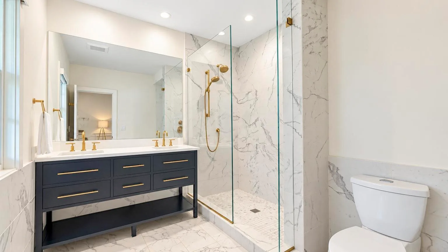 A bright bathroom with a double vanity and a glass-enclosed shower.