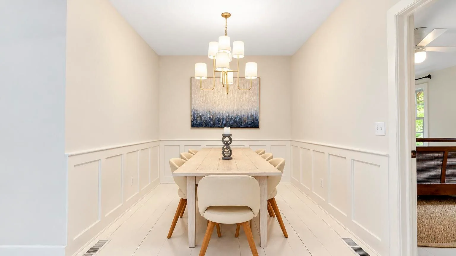 A dining room with a long table beneath a hanging light.
