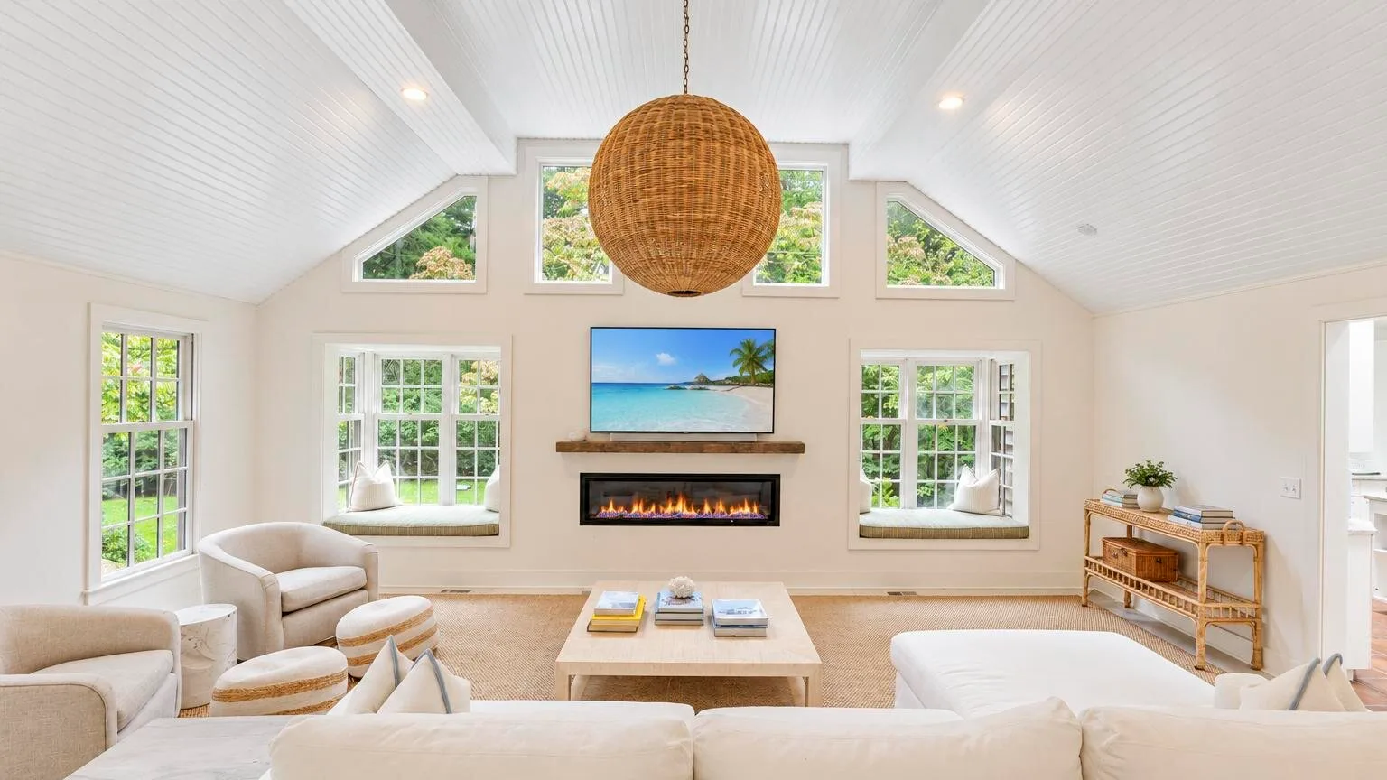 A bright living room with a fireplace, seating, and large windows.