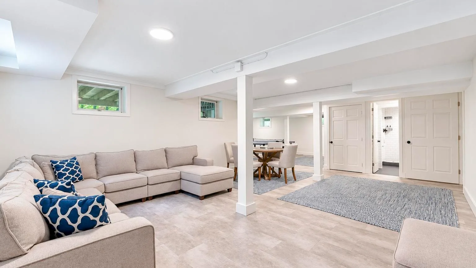 A bright living room with sectional seating and a dining area beyond.