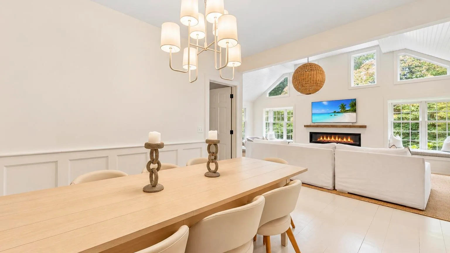 A bright dining area opens onto a living room with a fireplace and large windows.
