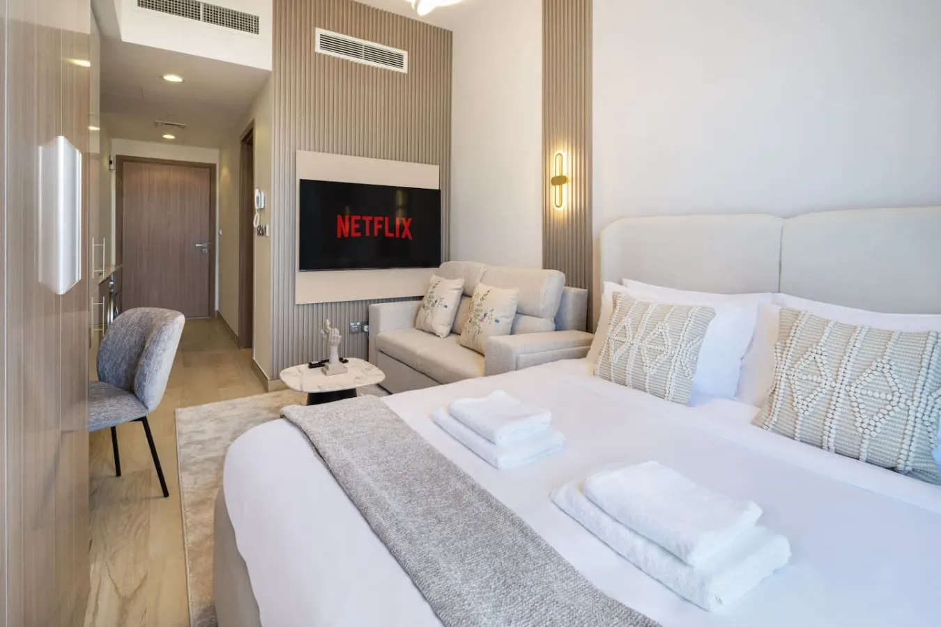 A bright bedroom with a large bed and a television mounted on the wall.