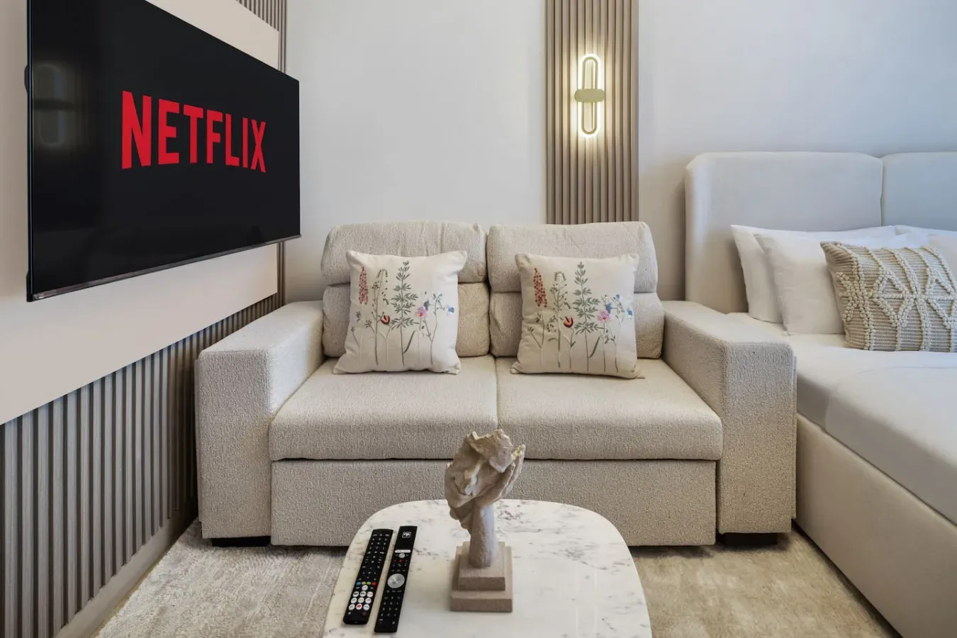 A living area with a sofa, wall-mounted television, and a small coffee table.