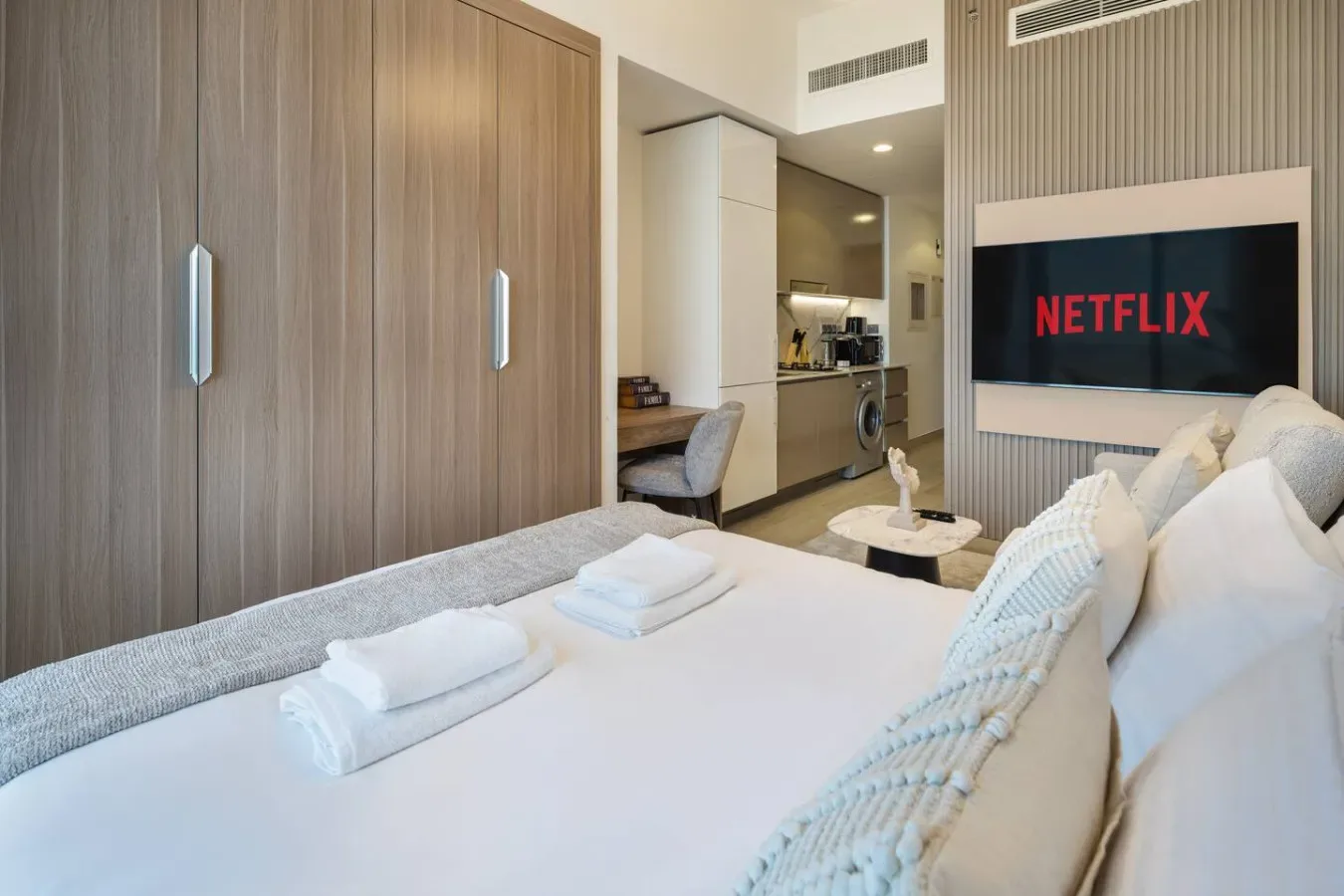 A bedroom with a neatly made bed and a wall-mounted television.
