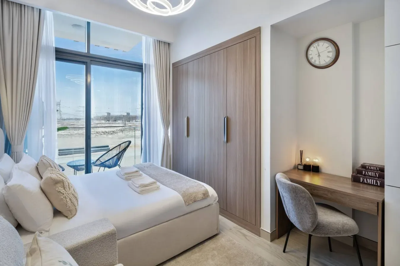 A bedroom with a large bed beside a window and a small desk area.