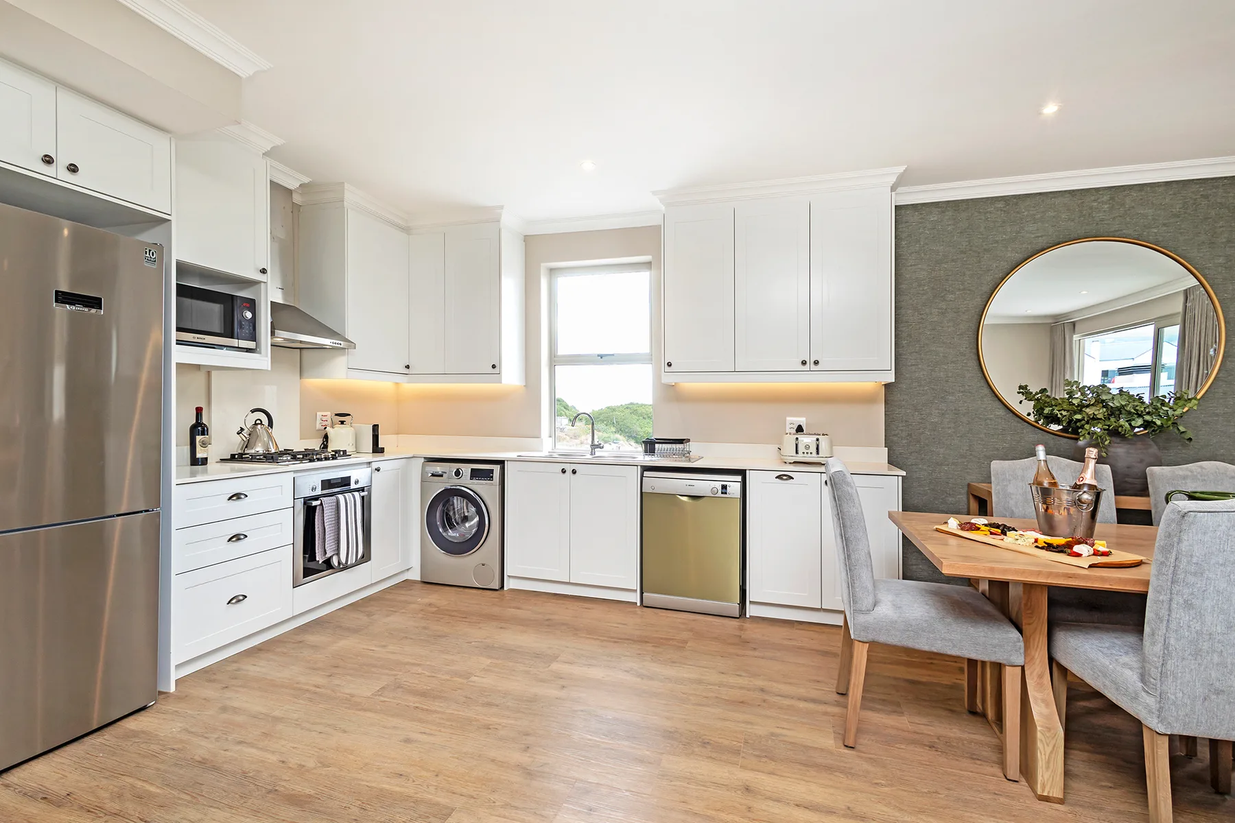 A bright kitchen with white cabinets opens onto a dining area.
