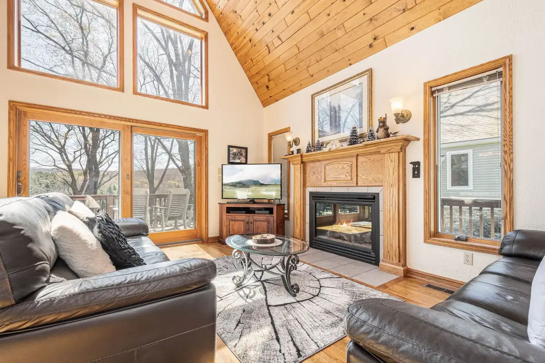 A living room with leather seating, a fireplace, and large windows.