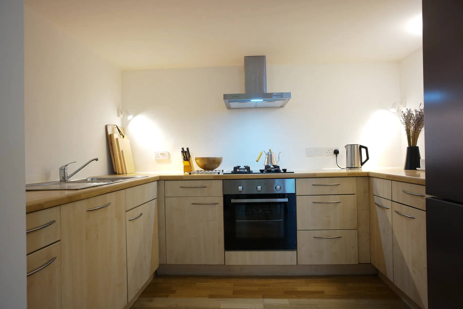A kitchen with wooden cabinetry, a stove, and a range hood.