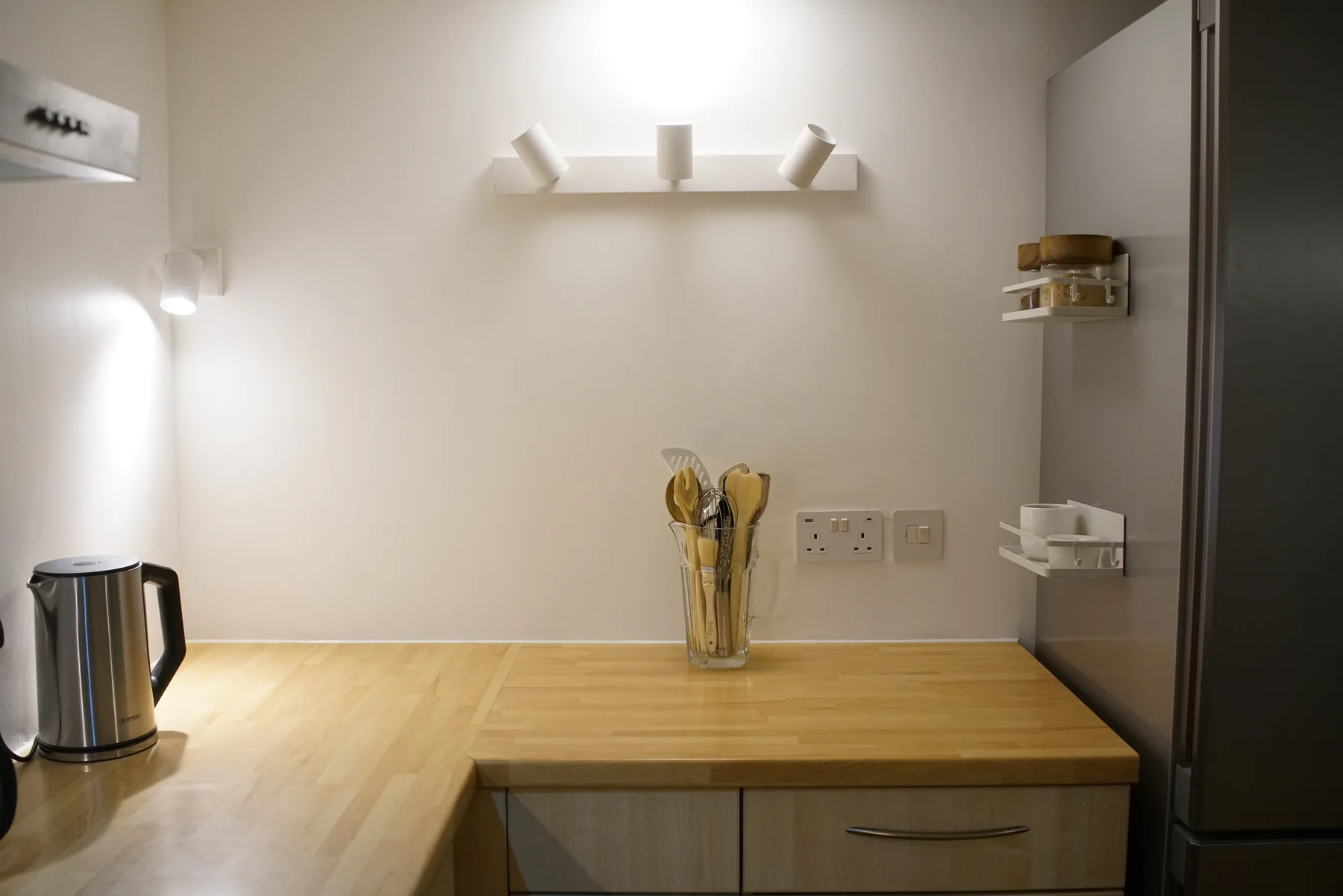 A kitchen counter with a kettle and utensils.