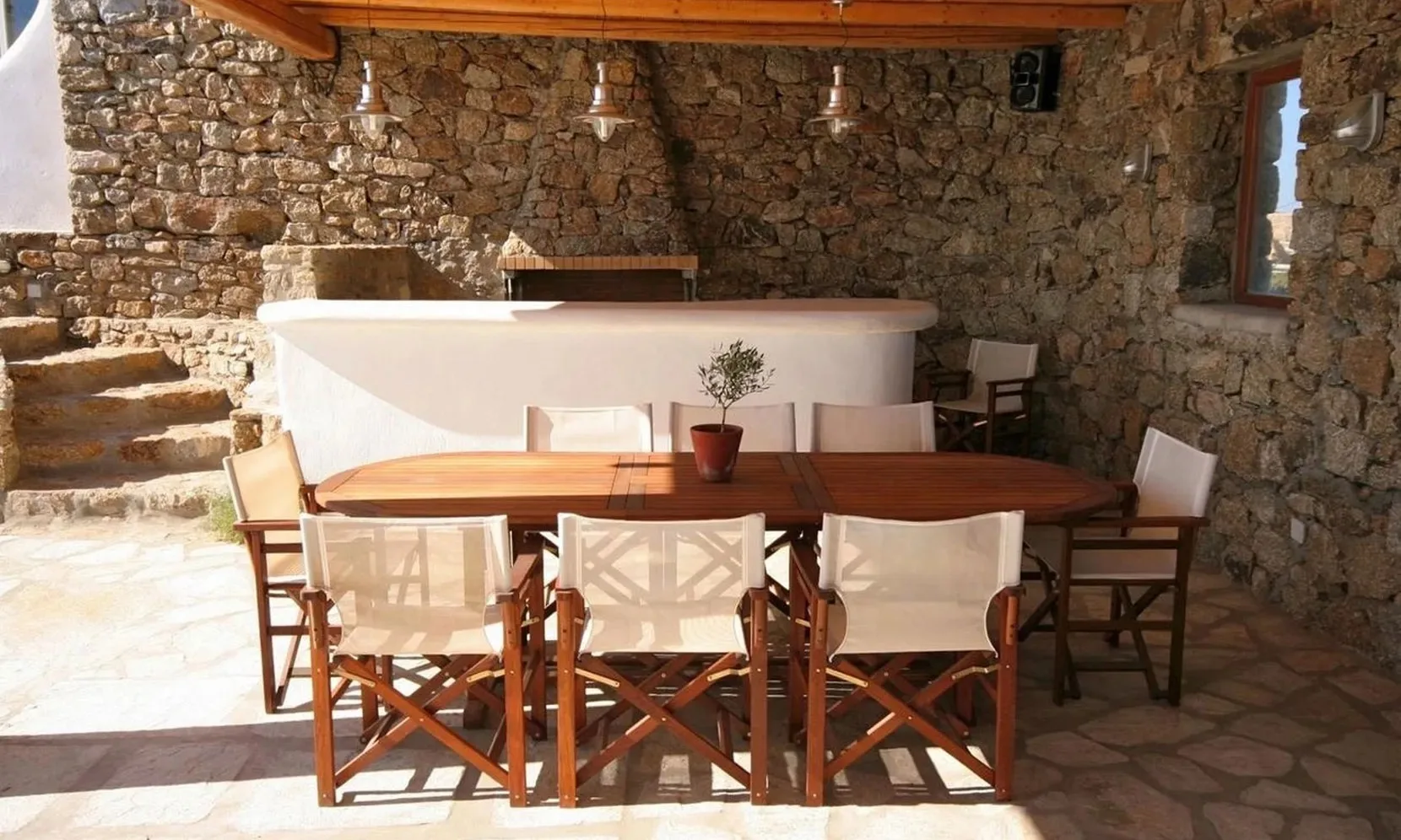 A stone-walled dining area with a wooden table and chairs.