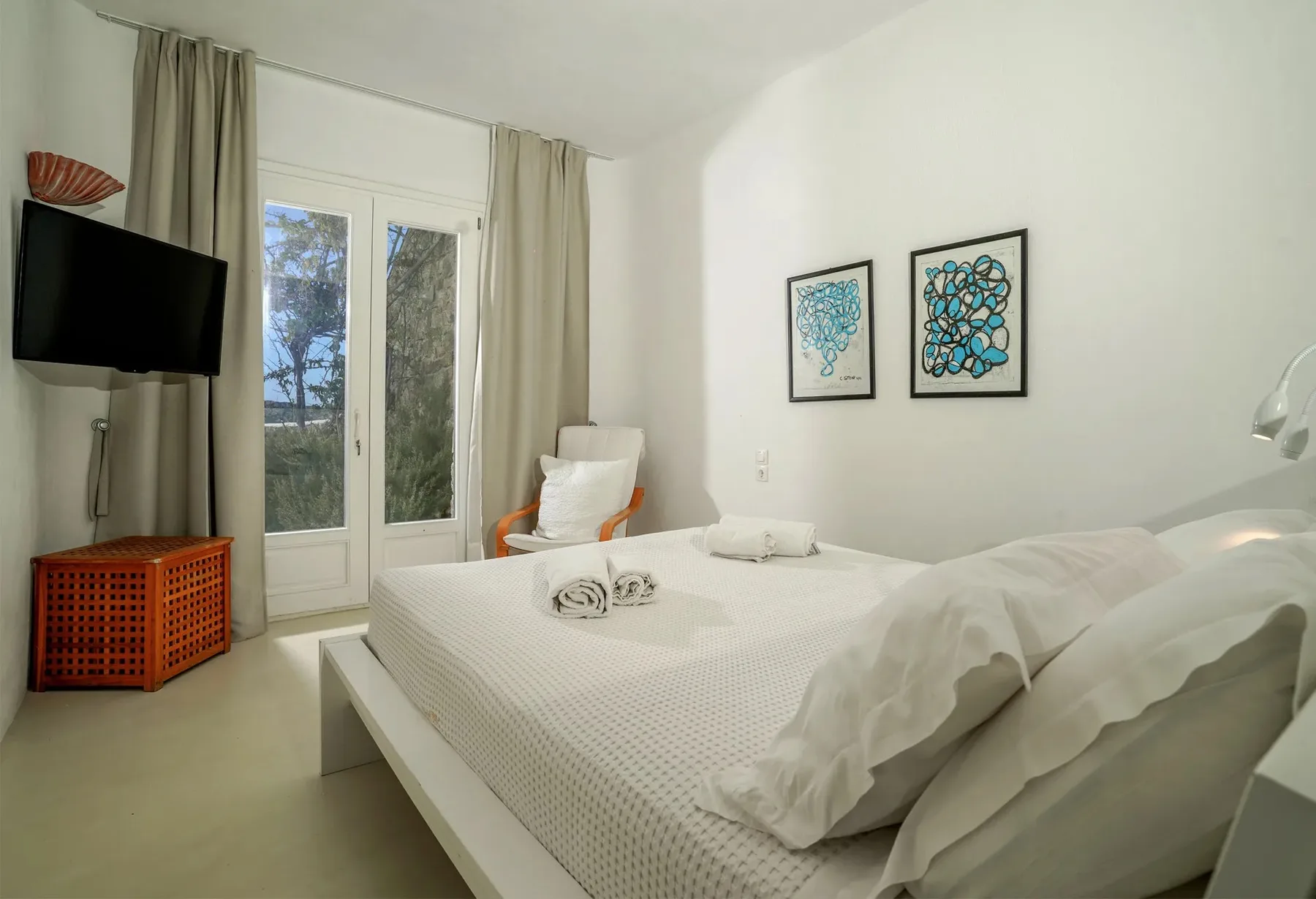 Un dormitorio luminoso con una cama doble y puertas de cristal que dan a un balcón.