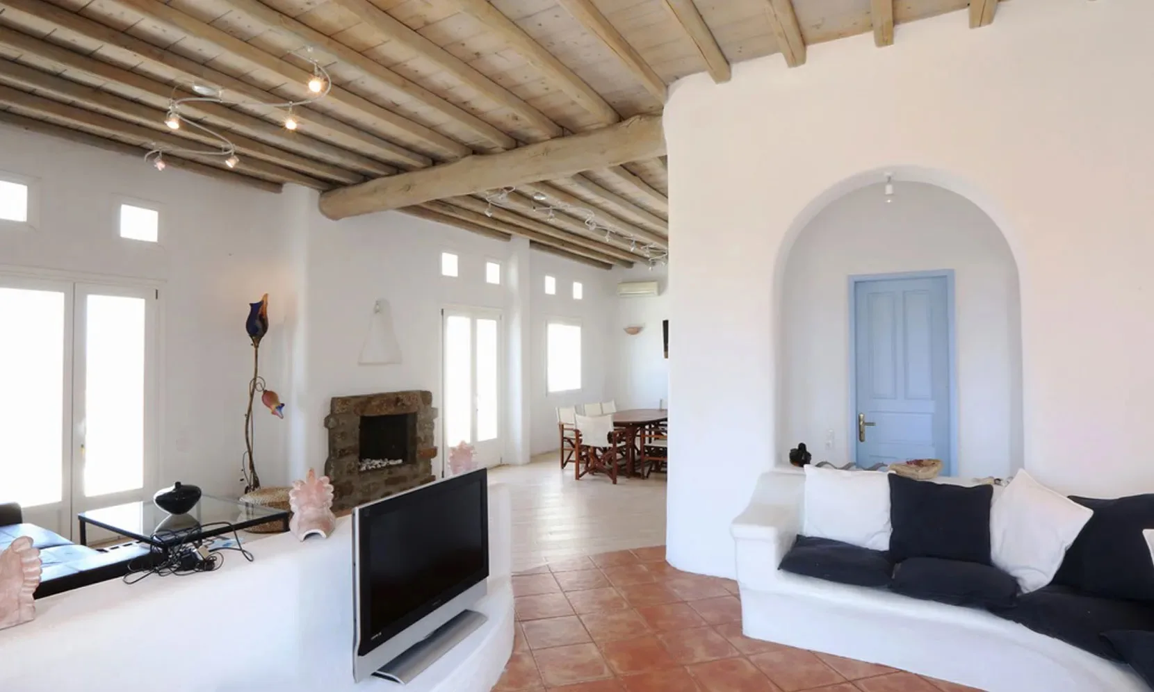 Una sala luminosa con asientos, un televisor y un techo con vigas vistas.