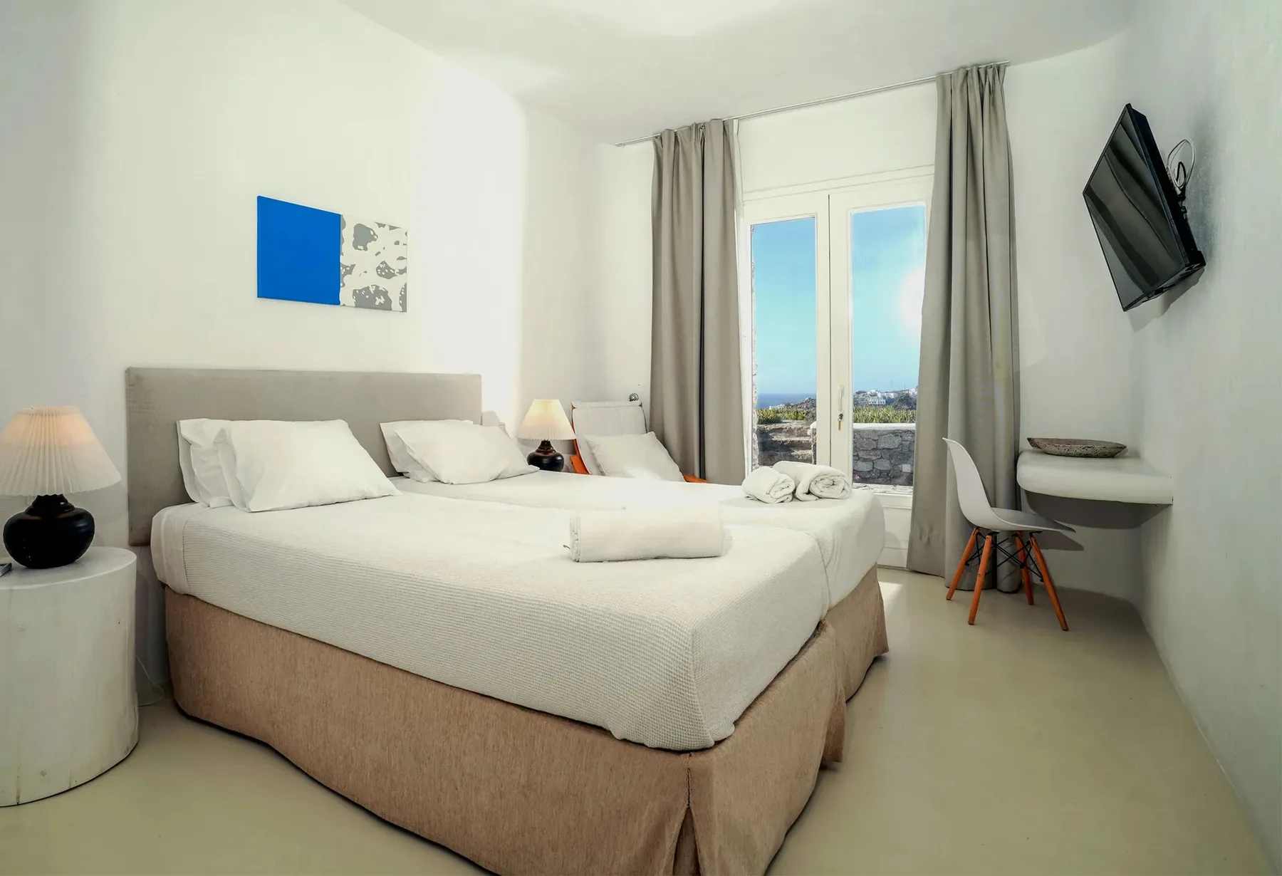 A bright bedroom with a large bed and a desk beside the window.