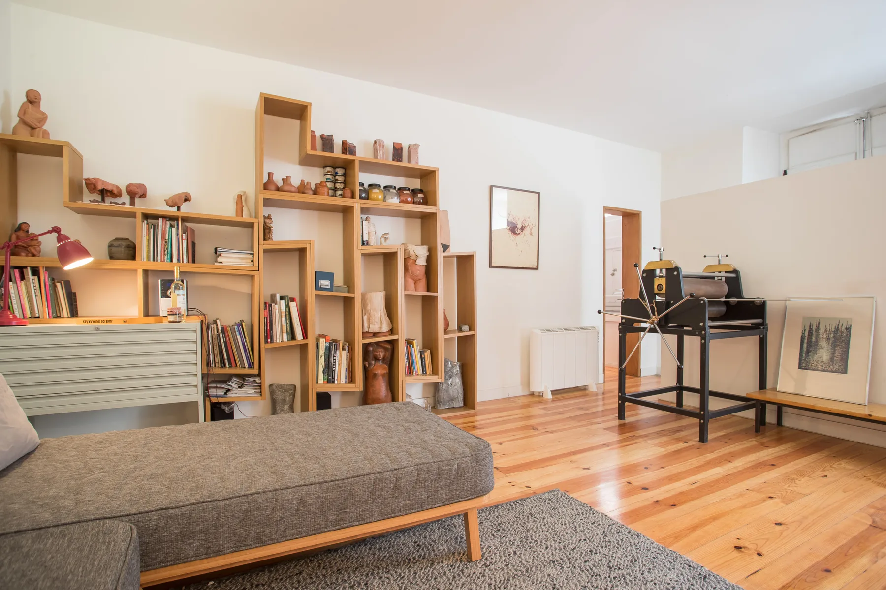 Una sala de estar luminosa con estanterías abiertas, asientos y suelo de madera.